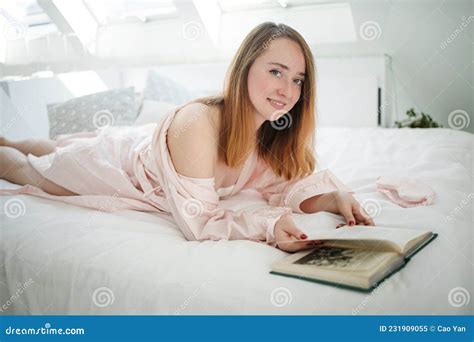 Relaxed Caucasian Girl In Pajamas Lying On Bed Near The Window In Light