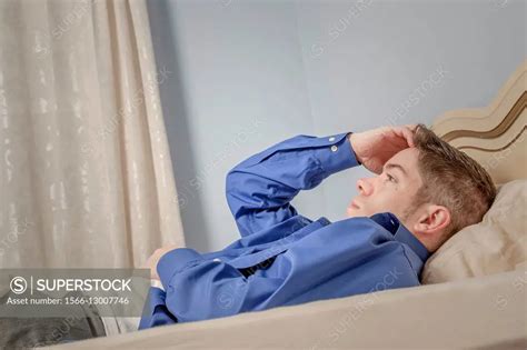 Young Man Dress Shirt Unbuttoned Lying On His Bed Superstock