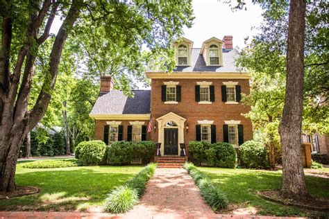 A Large Brick House Surrounded By Trees And Grass