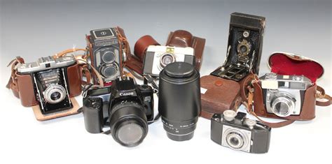 A Collection Of Assorted Cameras Lenses And Accessories Including A