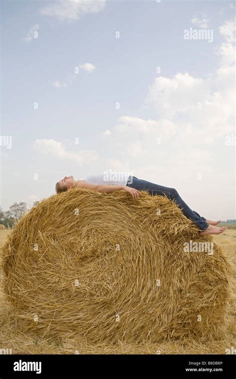 Young Woman Resting On Hay Bale In Field Stock Photo Alamy