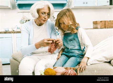 Gray Or White Haired Grandmother Showing Her Granddaughter How To Knit While Her Visit Sitting