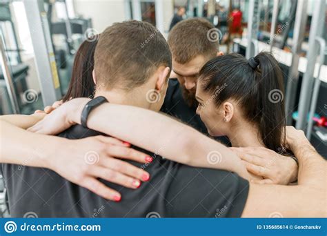 Group Of Young Sports People Embracing Together In Fitness Gym Backs