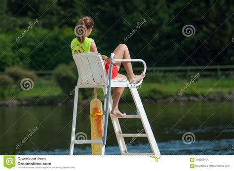 man lifeguard sitting on the chair under the sun umbrella near the swimming pool editorial image