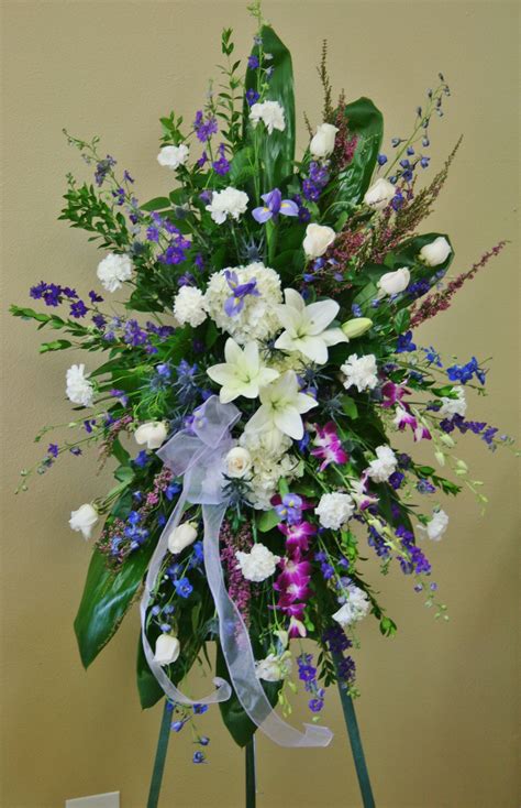 a beautiful sympathy standing spray in blue flowers white flowers and purple flowers this is a