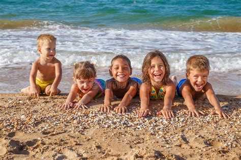 Cinco Niños Sonrientes Que Saltan En La Playa Imagen De Archivo