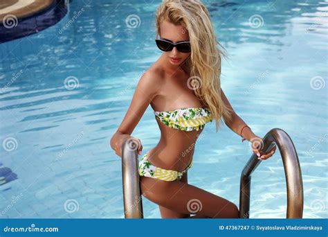 Woman With Blond Hair In Bikini And Sunglasses Posing In Swimming Pool