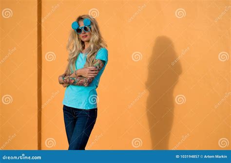 Beautiful Blonde In Sunglasses Posing At The Camera Portrait On The Background Of Bright Orange