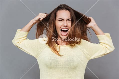 Portrait Of A Frustrated Angry Woman Screaming Out Loud And Pulling Her Hair Out Isolated On The