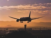 White Passenger Plane Flying over the City during Sunset · Free Stock Photo