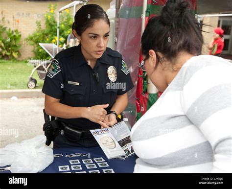 Hispanic Young Female Police Officer Speaks To Woman At Austin Police