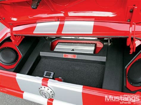 The Back End Of A Red And White Car With Speakers In Its Trunk