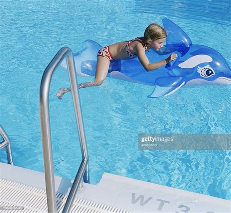 Girl Floating On Inflatable Dolphin In Swimming Pool Photo Getty Images