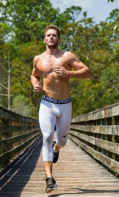 A Shirtless Man Running On A Bridge In White Pants And No Shirt With