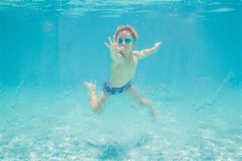 Boy Having Fun Playing Underwater In Swimming Pool On Summer Vacation