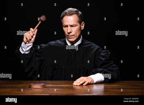 Judge In Judicial Robe Sitting At Table And Hitting With Gavel Isolated On Black Stock Photo Alamy