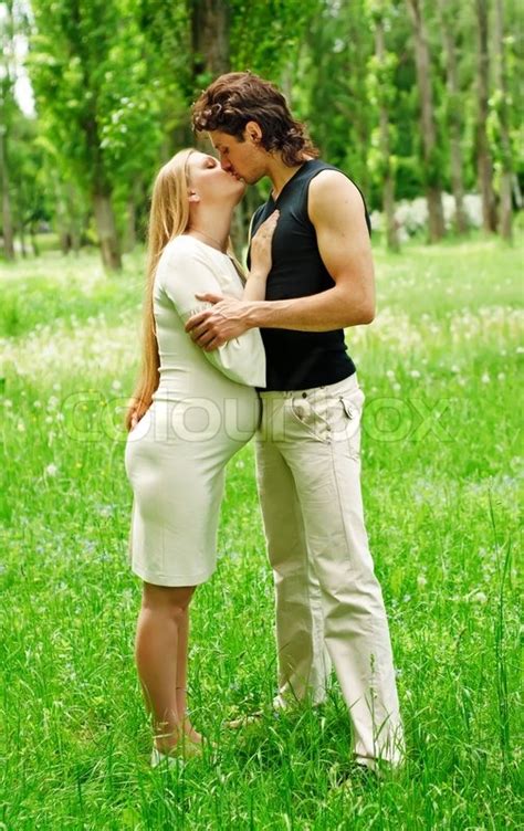 schöne schwangere frau mit ihrem mann küssen im park stockfoto colourbox