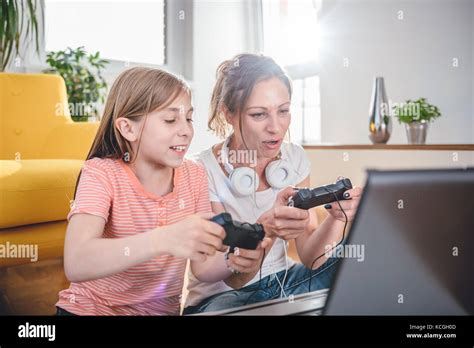 Mother And Daughter Playing Video Games On Laptop At Home Stock Photo