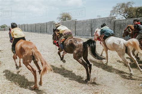 Rear View Of Jockeys Riding Racehorses During Horse Racing Stock