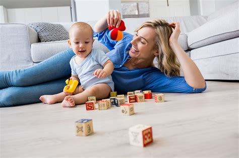 Madre Que Mira Al Bebé Jugando Con Juguetes En La Sala De Estar Foto