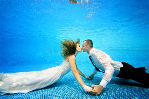 The Bride And Groom In Wedding Dresses Kissing Underwater In The Swimming Pool Portrait