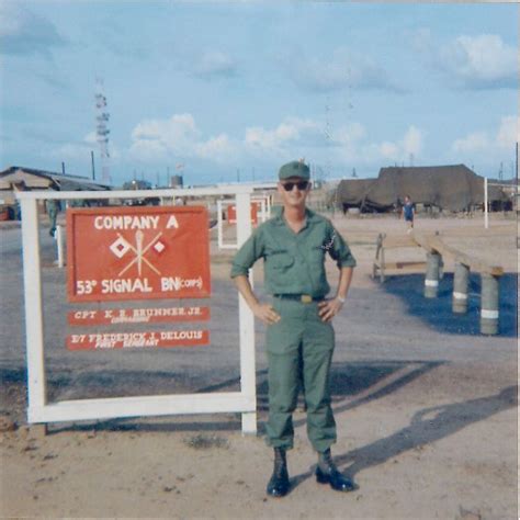 A Man In Uniform Standing Next To A Sign