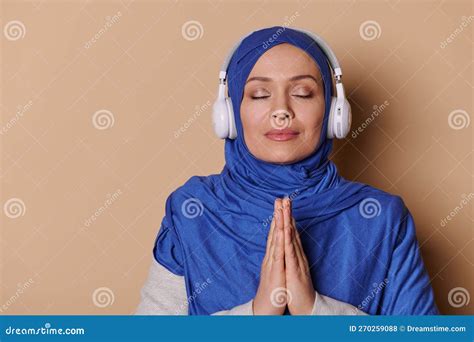 Arab Muslim Woman With Her Eyes Closed In A Hijab Keeps Hands Palms Together Listens To