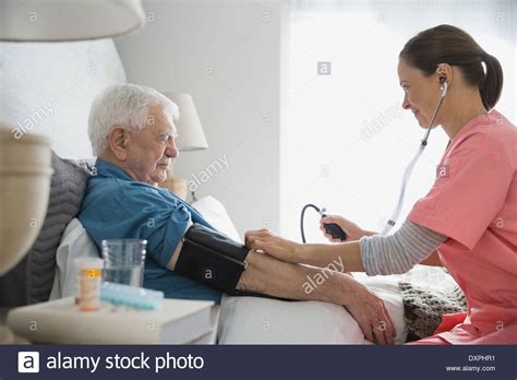 Home Care Nurse Taking Senior Mans Blood Pressure Stock Photo Alamy
