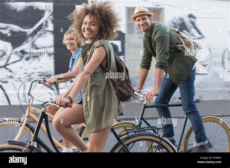 Portrait Smiling Friends Riding Bicycles On Urban Street Stock Photo