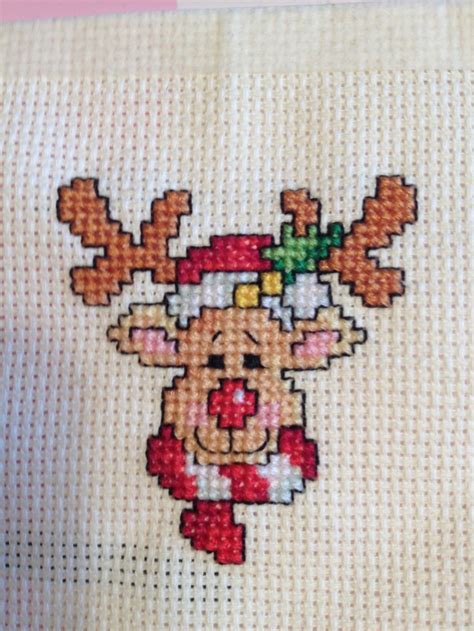 a cross stitch christmas card with a reindeer wearing a santa hat