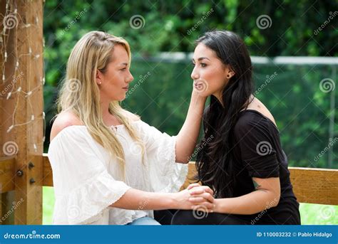 een paar van trotse lesbische zitting in in openlucht het bekijken elkaar en gaat kussend op een