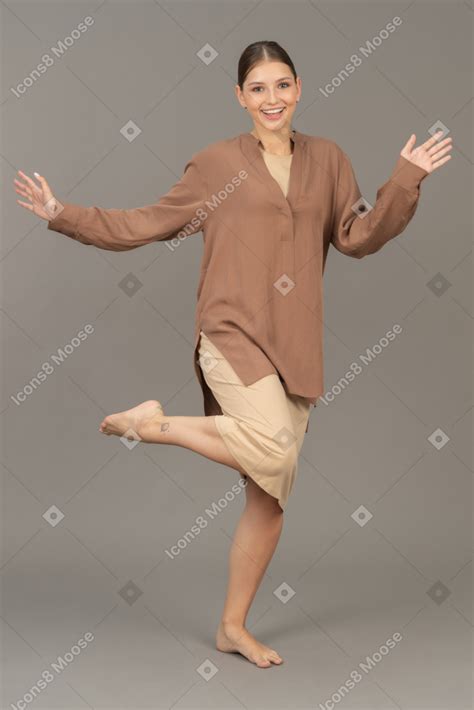 Фото Вид спереди на молодую женщину стоящую босиком на одной ноге с широко раскрытыми руками