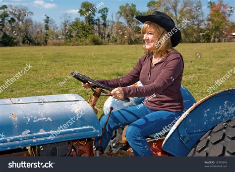 Beautiful Mature Woman Driving A Tractor On The Farm