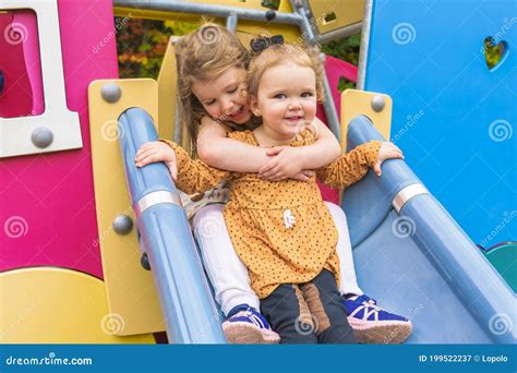 Happy Smiling Sister Girl Playing At Playground Outdoors In A Nice Park