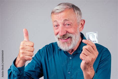 Caucasian Old Senior Man Holding Packed Rubber Latex Condom In Studio