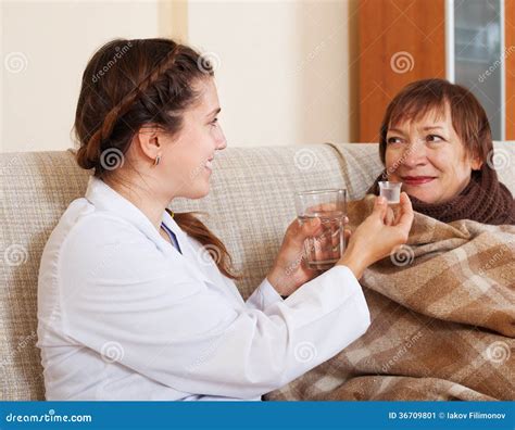 Enfermera Sonriente Que Cuida Para La Mujer Madura Enferma Imagen De