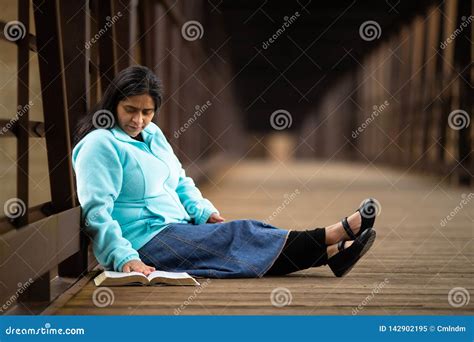 hispanic woman sitting and reading bible on a bridge stock image image of adult praying