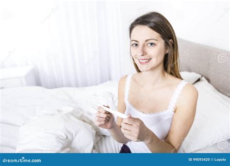mujer joven en el dormitorio en casa que lleva en prueba embarazada del control blanco foto de