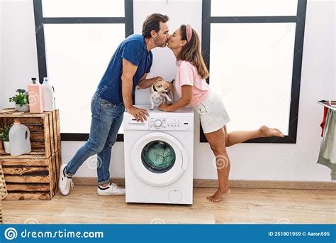 Middle Age Man And Woman Couple Kissing And Washing Clothes At Laundry