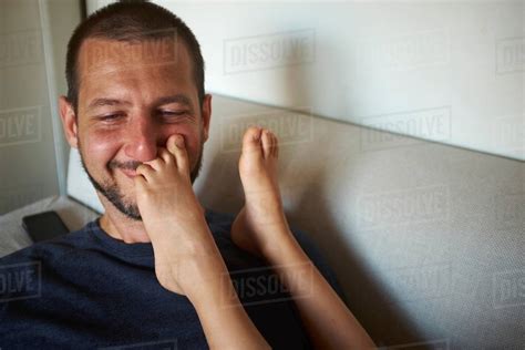 Father Sitting On Sofa Sons Bare Feet Touching His Face Stock Photo