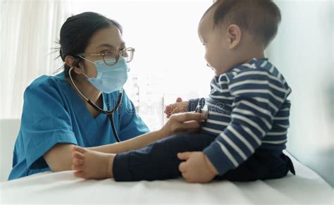 Asian Doctor Wearing Protective Face Mask Examining Baby Stock Image