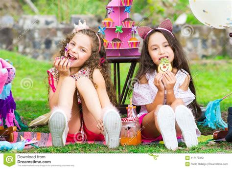 Two Cute Little Sisters In The Garden Curly Girl Eating A Cupcake And