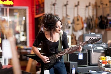Young Woman Playing Electric Guitar In Music Store Stock Photo Dissolve