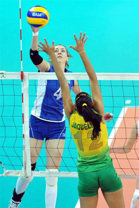 Two Women Playing Volleyball In Front Of The Net