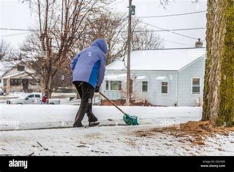 Woman Shoveling Snow From Sidewalk In West Point Nebraska Stock Photo