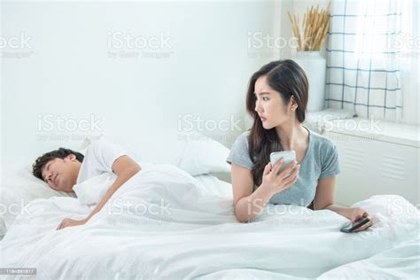 Wife Spying The Phone Of Her Husband While Man Sleeping In Bed At