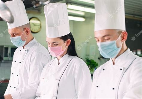 Premium Photo Chefs In Protective Masks And Gloves Prepare Food In