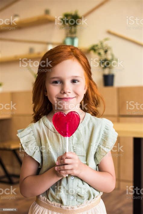 Beautiful Redhead Girl Eating Heart Shaped Lollipop And Looking At