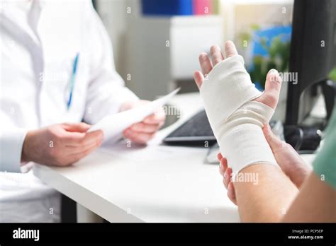 Injured Patient Showing Doctor Broken Wrist And Arm With Bandage In