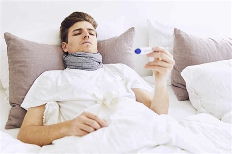 Sick Man Examining Temperature With Thermometer While Resting On Bed At